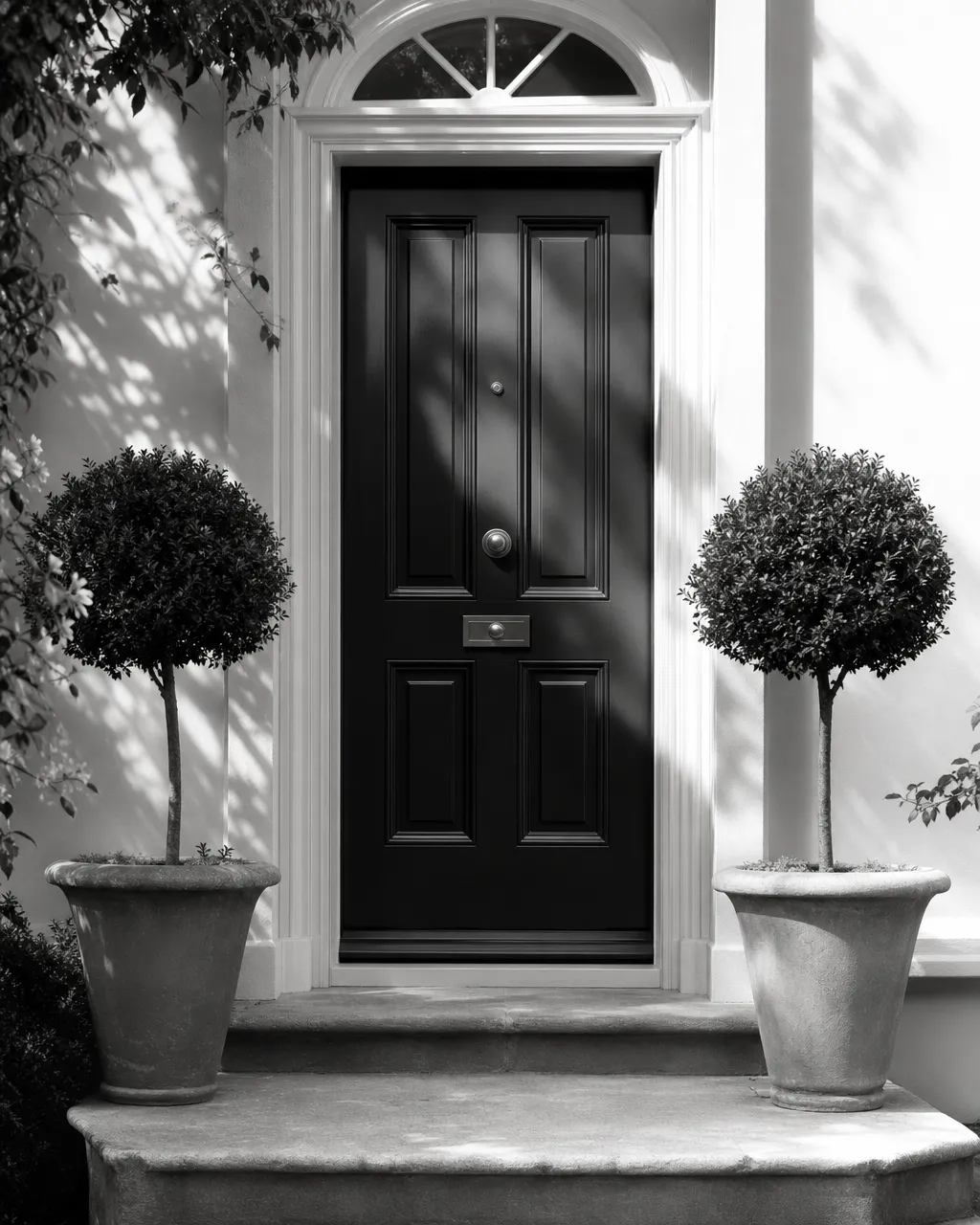 A freshly painted front door flanked by potted topiaries in soft morning light