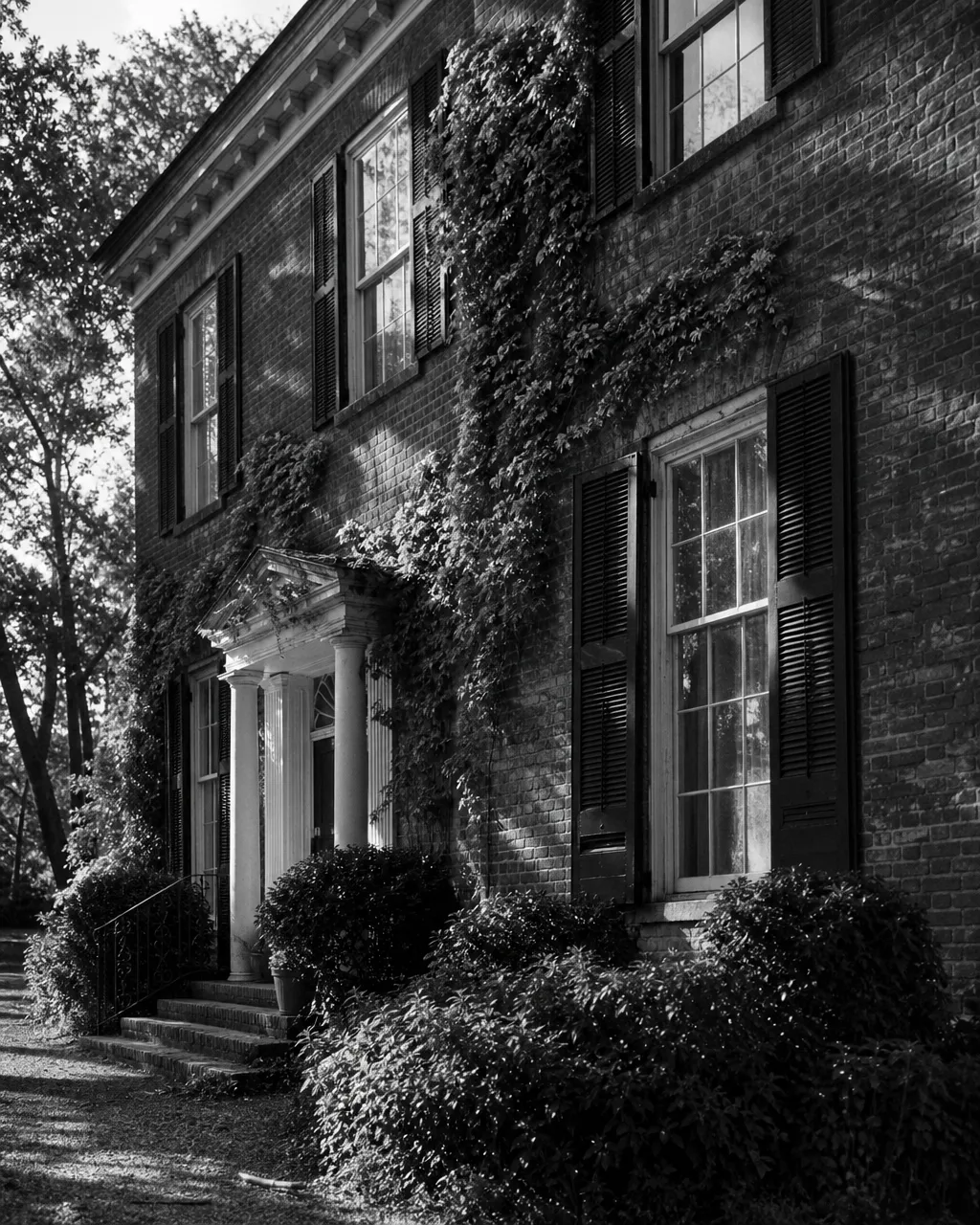 A stately Georgian brick facade with climbing ivy and weathered shutters