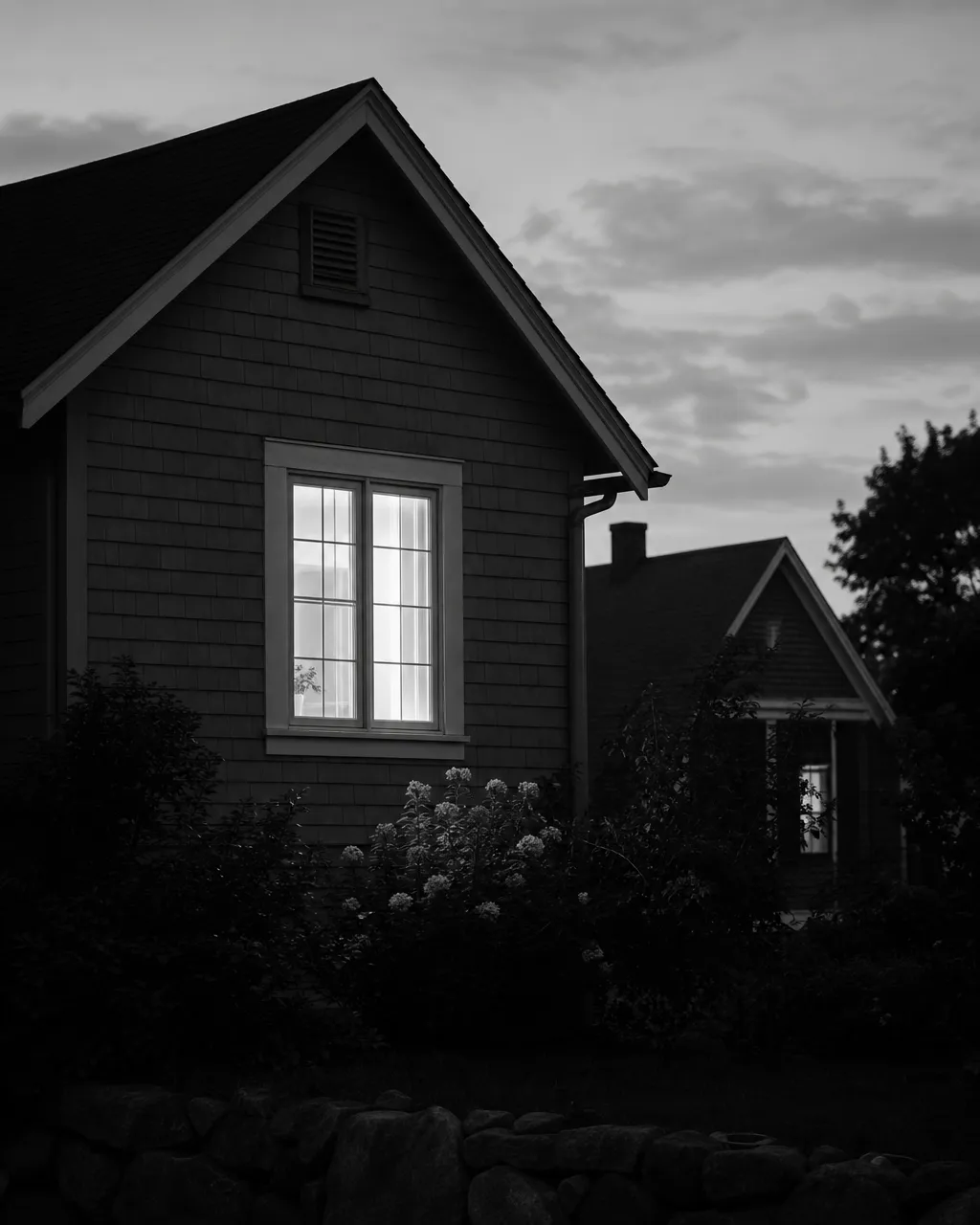 A single lit window glowing at dusk in a quiet neighborhood