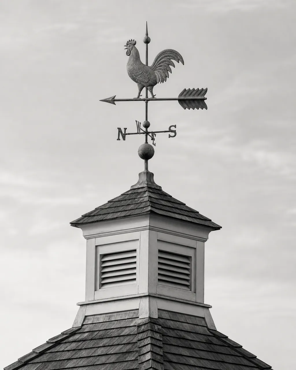 A copper weathervane atop a cupola against a pale morning sky